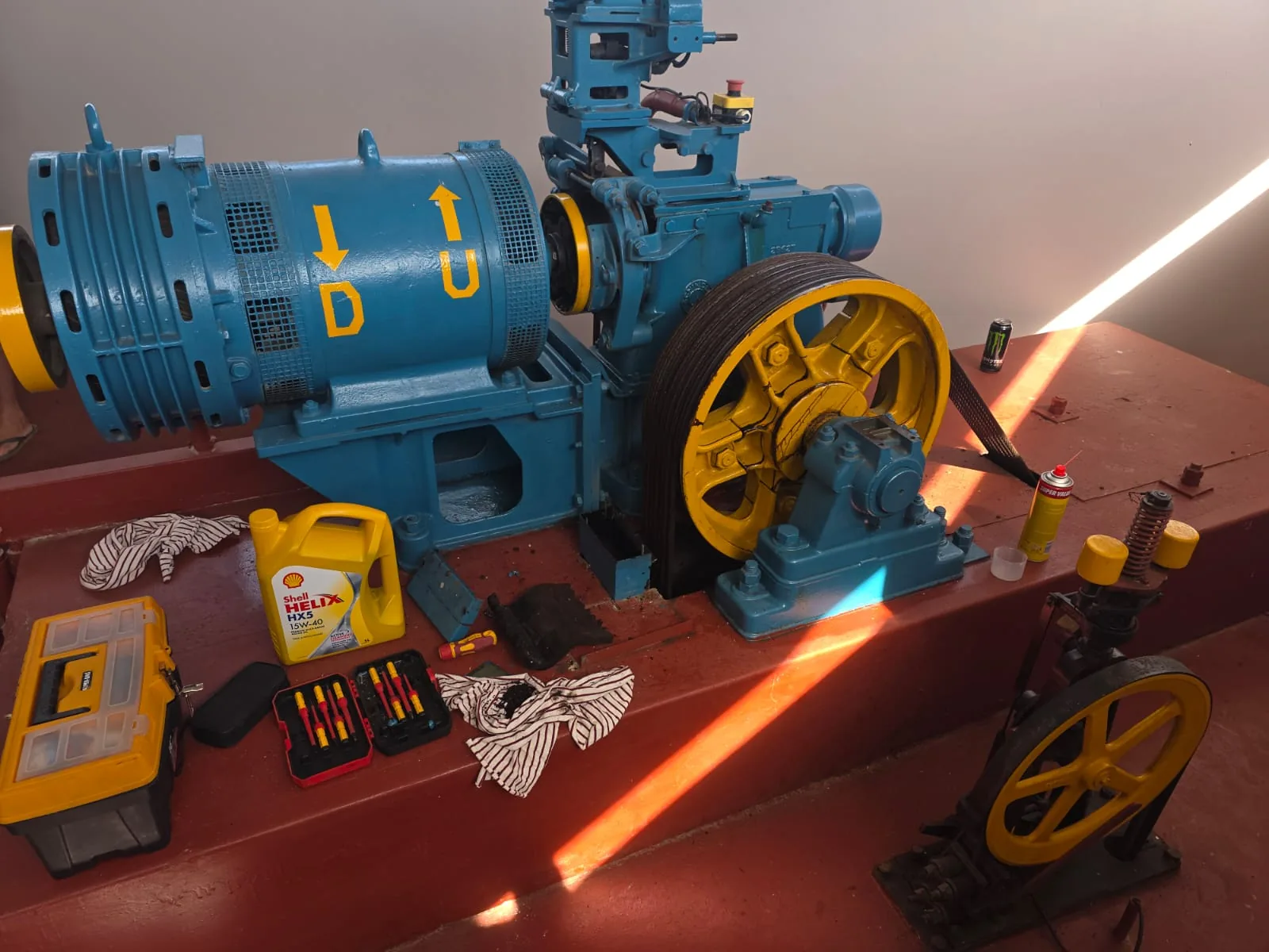 Blue lift machinery with a yellow wheel and tools nearby.