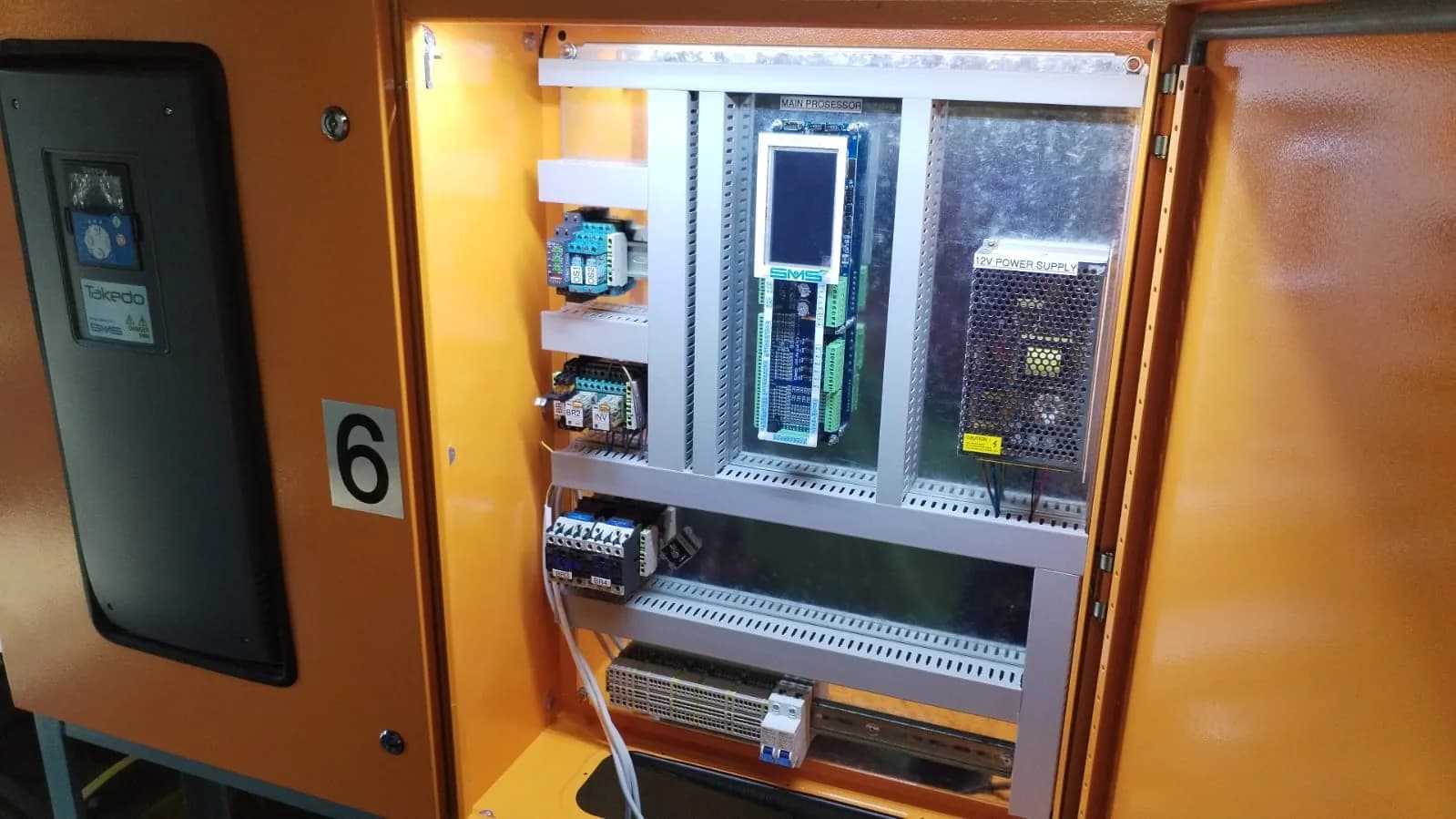 Open orange lift control cabinet showing its internal electronics.