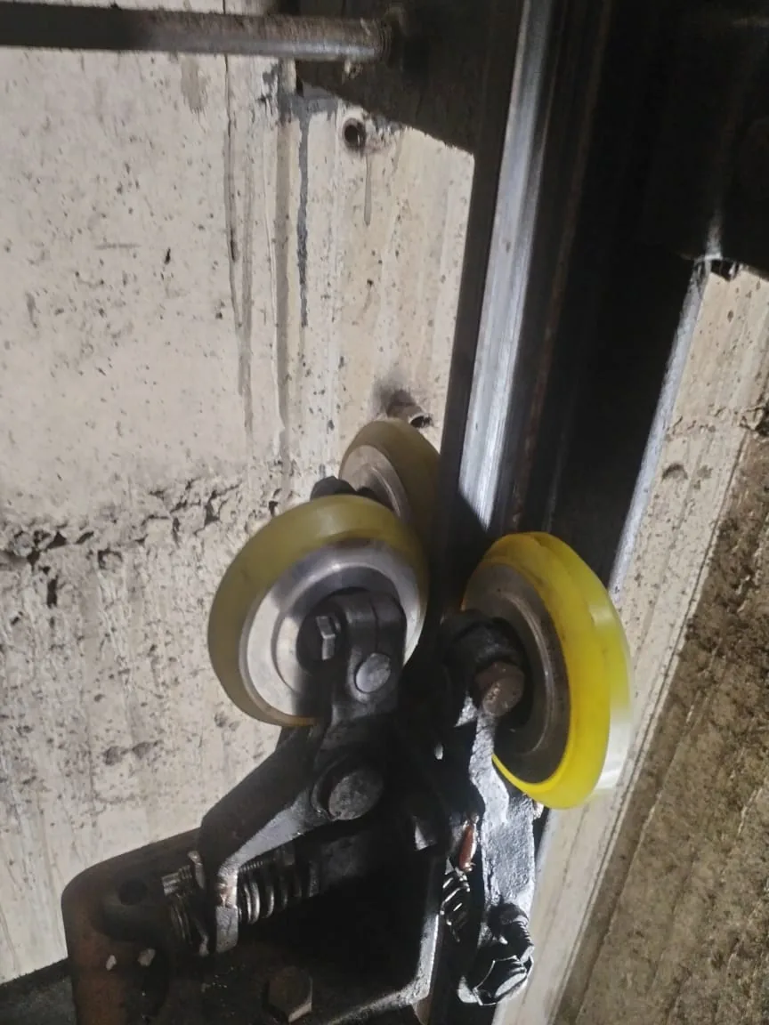 Roller-guide assembly beside a lift shaft rail.